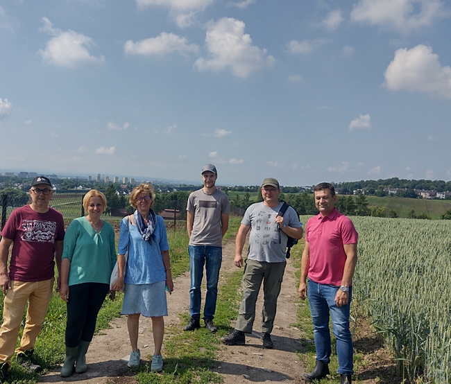 Prof. Szewczyk, prof. Joanna Dłużniewska, mgr. Anna Krzysztofik wraz ze studentami, na tle widoku rozpościerającego się z pól SDOO Węgrzce